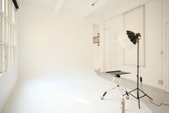 Estúdio de fotografia vazio equipado com lâmpadas, pronto para uma sessão fotográfica.