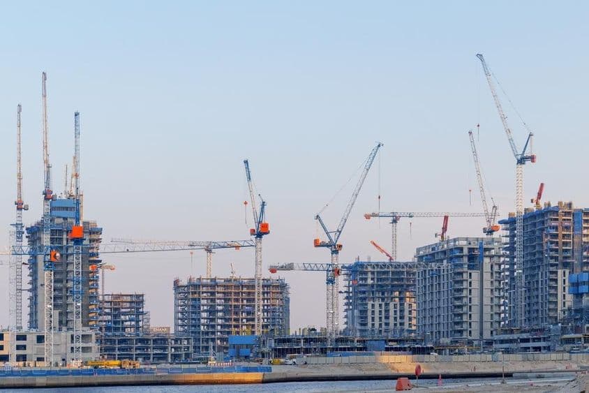 Construção imobiliária no Dubai Creek Harbor, guindastes, torres inacabadas.