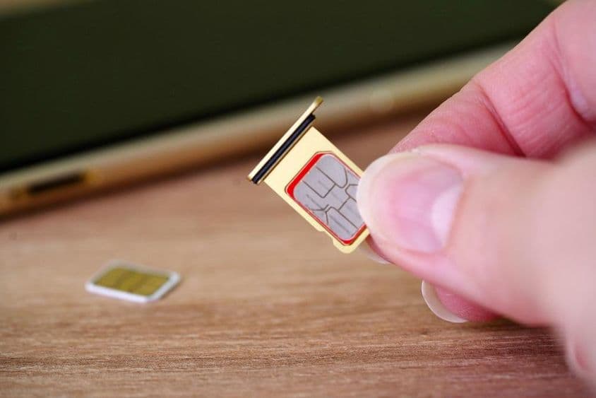 Pessoa inserindo um cartão SIM na parte de trás de um celular.
