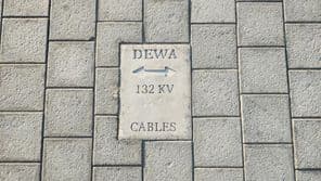 Placa avisando de cabos no chão de pedras em Dubai.