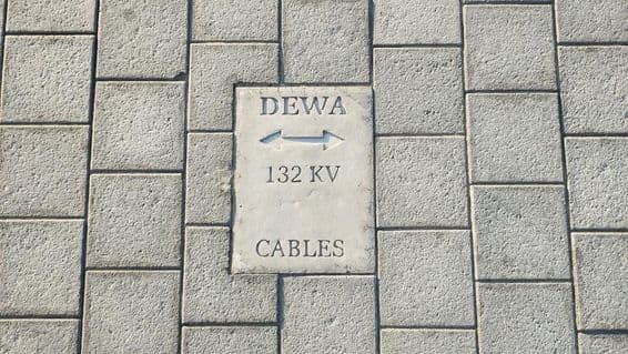 Placa avisando de cabos no chão de pedras em Dubai.