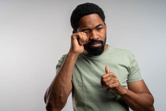 Uma pessoa esfregando os olhos desconfortavelmente, sentindo-se irritada e cansada.