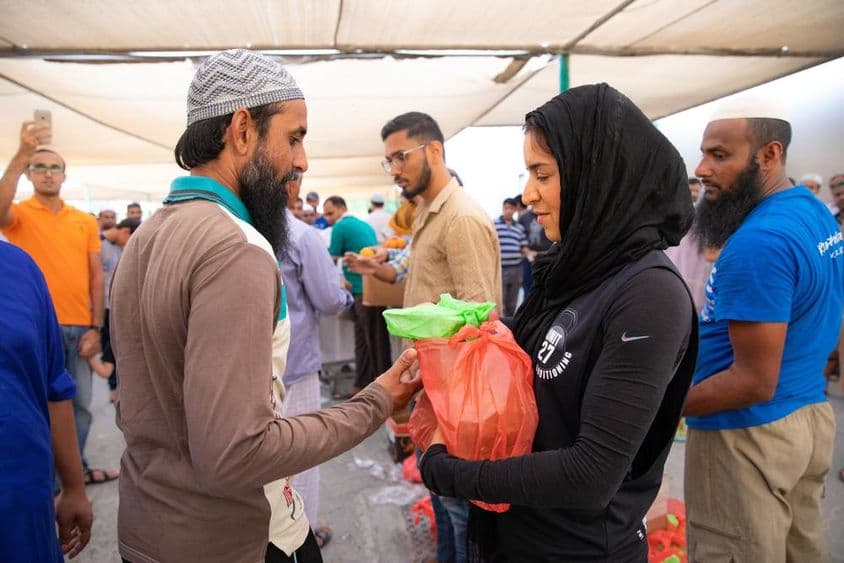 Voluntários distribuem pacotes de alimentos para trabalhadores durante a refeição Iftar.