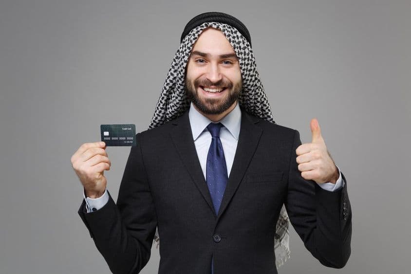 Empresário muçulmano árabe sorridente com um cartão de crédito.
