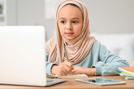 Menina muçulmana fazendo lição de casa em casa usando hijab.