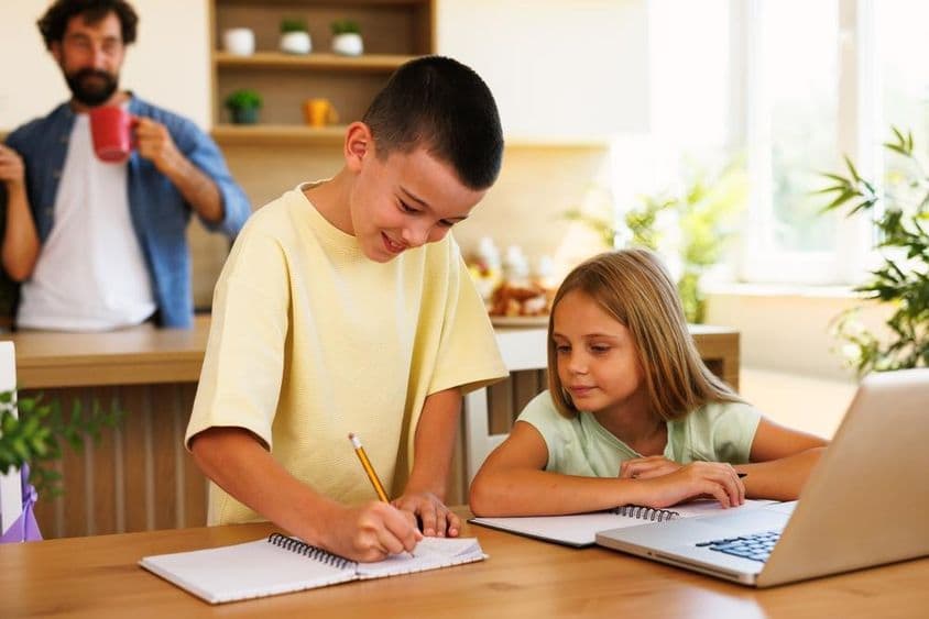 Irmãos fazendo lição de casa em casa usando laptop.