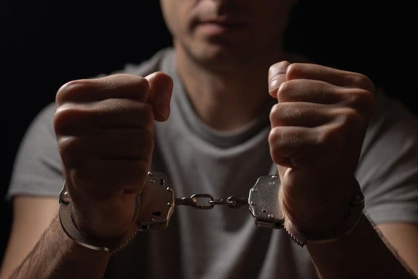 Mãos algemadas à frente.