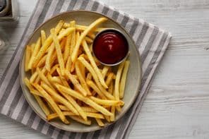 Batatas fritas caseiras e ketchup em um prato.