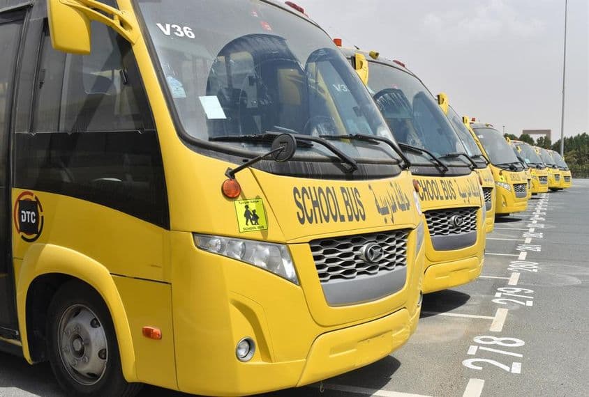 Vários ônibus escolares amarelos alinhados em um estacionamento em Dubai.