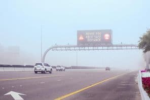 Estrada enevoada com uma placa mencionando Manter Distância.
