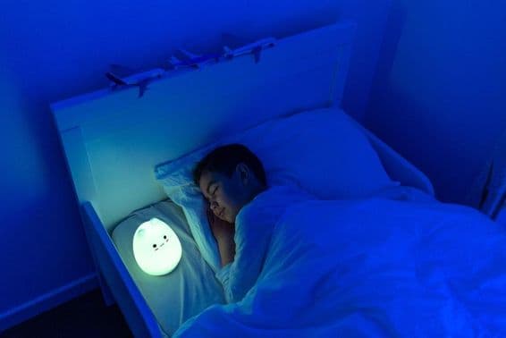 menino dormindo com luminária de cabeceira LED.