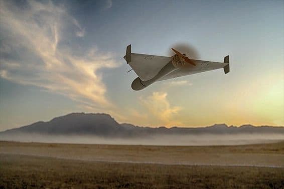Um drone militar kamikaze voando sobre montanhas desérticas.