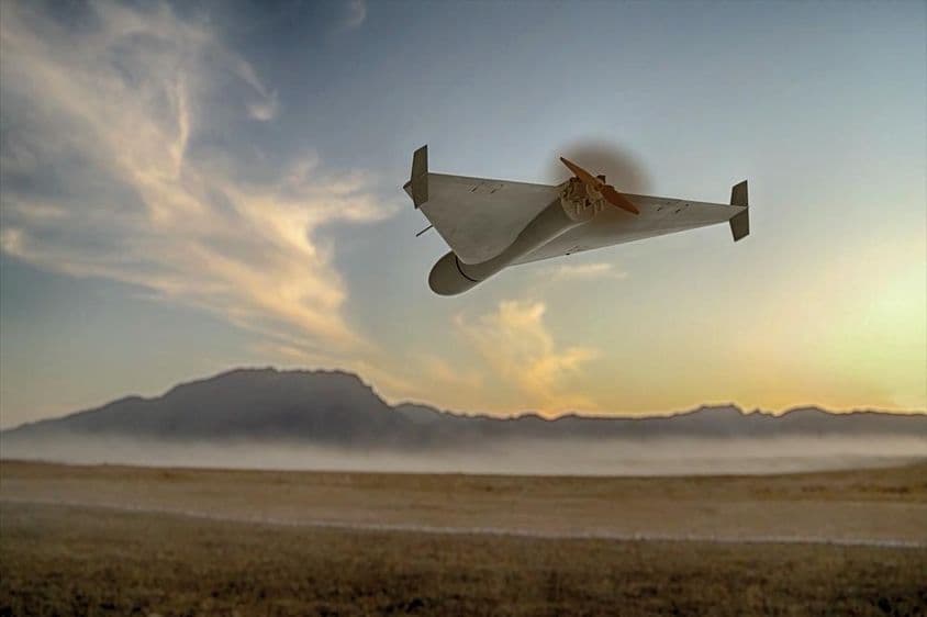 Um drone militar kamikaze voando sobre montanhas desérticas.