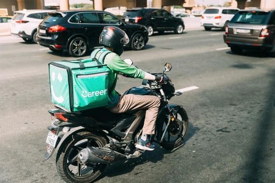 Entregador da Careem entregando comida em uma scooter.