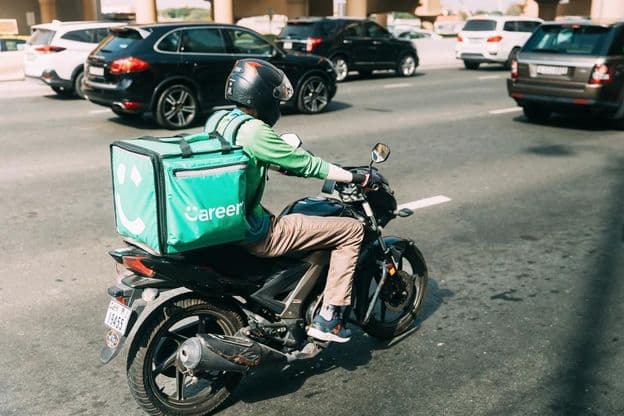 Entregador da Careem entregando comida em uma scooter.