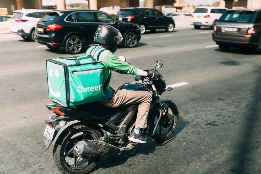 Entregador da Careem entregando comida em uma scooter.