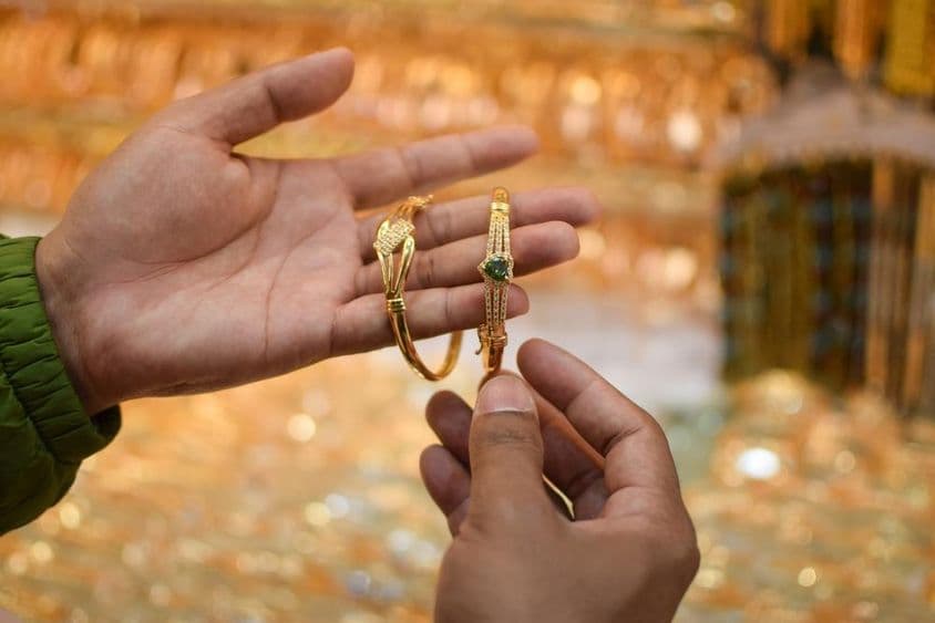 Uma mão experimentando uma pulseira de ouro de luxo em uma loja de joias.