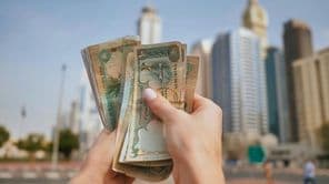 A moeda dos Emirados Árabes Unidos contra o pano de fundo dos arranha-céus de Dubai.