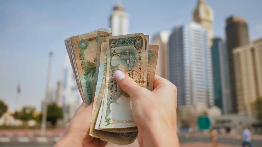 A moeda dos Emirados Árabes Unidos contra o pano de fundo dos arranha-céus de Dubai.