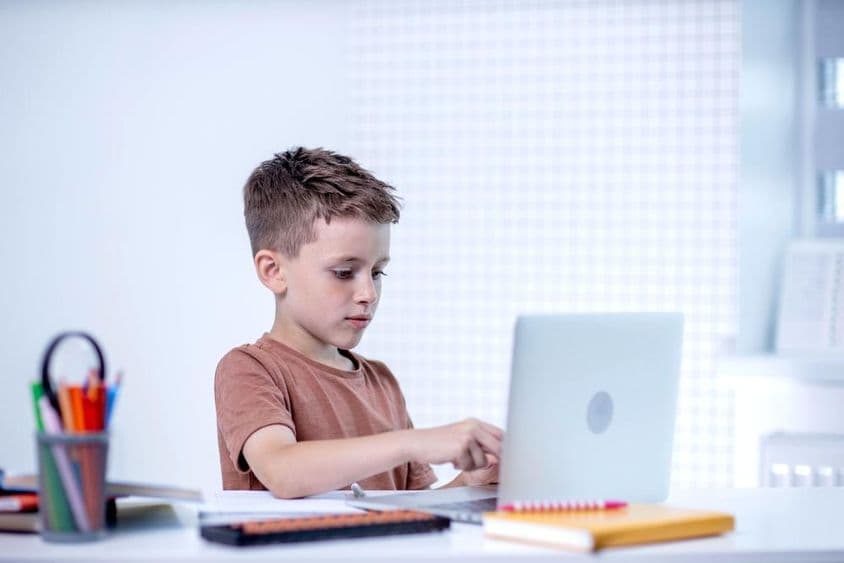 Criança escolar conversando com professor via videoconferência no computador
