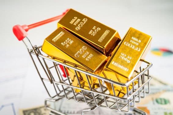 Barra de ouro em um carrinho de compras sobre notas de dólar americanas