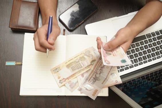 Um homem contando uma pilha de notas de dirham dos Emirados Árabes Unidos.