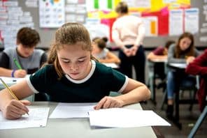 Estudantes realizando exames em uma sala de aula.