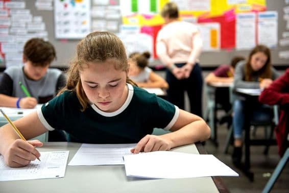 Estudantes realizando exames em uma sala de aula.