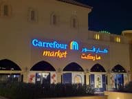 Logotipo iluminado do mercado Carrefour com nome da marca em árabe