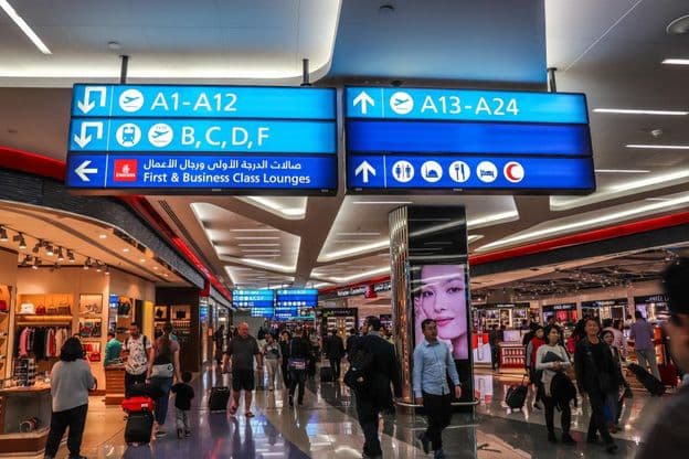 Passageiros caminhando em direção aos portões de embarque no Aeroporto Internacional de Dubai