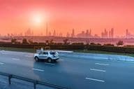 Rodovia e skyline de Dubai ao pôr do sol.
