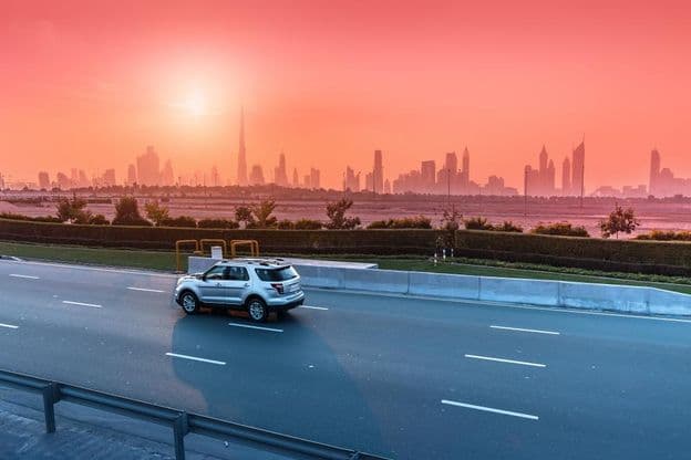 Rodovia e skyline de Dubai ao pôr do sol.