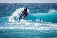 Jetski atinge a água acima de uma onda quebrando