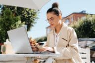 Empresária estilosa usando óculos trabalhando em um laptop